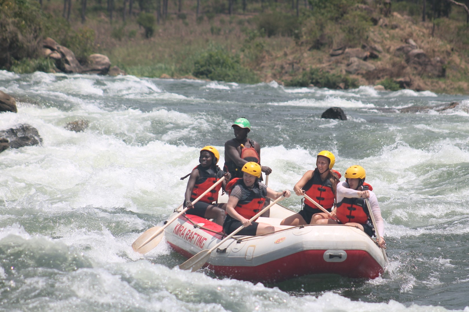 Kiira Rafting crew paddling a raft through a White Nile rapid